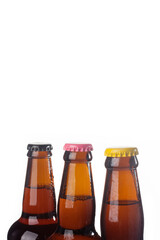 Row of brown beer bottles over white background. Beer with colored caps. Close up view of drinks with copy space.