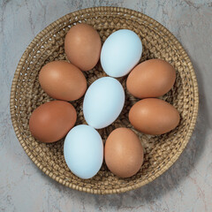 several fresh chicken eggs in a straw basket on a wooden background. Healthy eating concept.