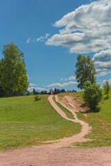 a narrow path among the fields of a country park near St. Petersburg against a blue summer sky
