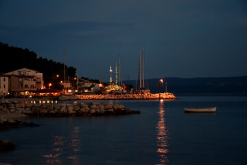 Calm and warm summer night the seacoast in Croatia with lights reflecting in the water.