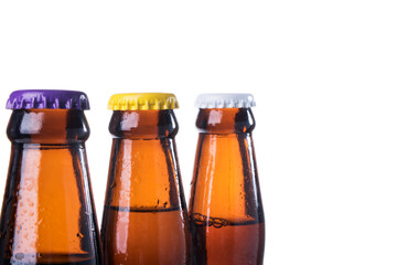 Brown beer bottles over white background. Beer with colored caps. Close up view of drinks with copy space.