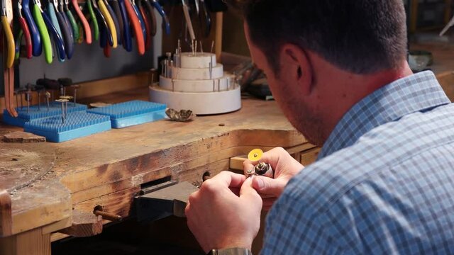 Male Jeweler Uses A Rotary Tool While Working With A Ring. Male Jeweler Uses A Rotary Tool While Working With A Ring. Close up video as male jeweler uses abrasive disc to clean the ring.