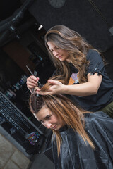 Profesional de peluquería trabajando, peinando, tiñendo y cortando cabello.