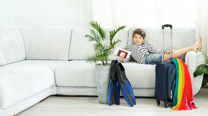 Tourist boy with a suitcase and flippers stays at home during the coronavirus pandemic. Cancellation of leave and closing of borders between countries. Flight cancellation © Irina