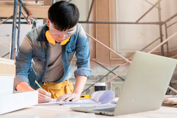 asian engineer male with uniform working with laptop and home mockup model analysis construction result with application technology at site construction home renovate and improvment background