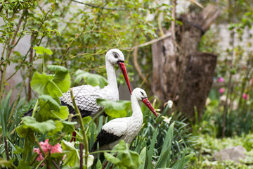 The figure of a pair of stork birds stands in the garden