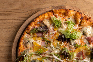 Pizza with chicken breast, peach, dor blue cheese, mozzarella and ham.