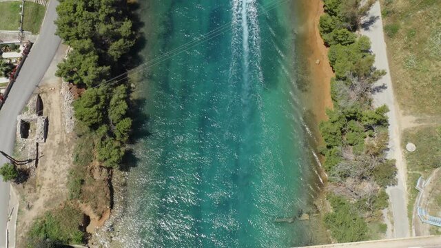 Tilt up aerial shot of sea strait and motorboat sailing. Halkidiki, Greece.