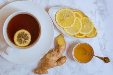 simple image of a cup of black tea with a slice of lemon, honey and ginger,  on white background