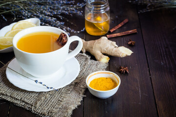 turmeric tea with cinnamon and ginger in a white cup on wooden table 
