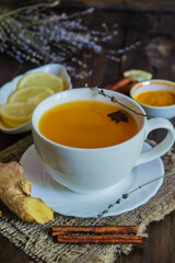 turmeric tea with cinnamon and ginger in a white cup on wooden table 
