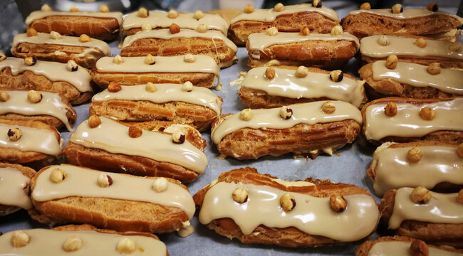 Close up French dessert eclairs with filling, glaze and nuts. Backgrounds