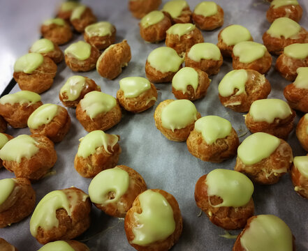 Close up French dessert eclairs with filling and pistachio glazes. Backgrounds