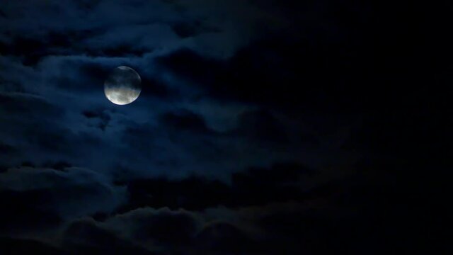 Full moondown through the clouds on dark blue night sky. 1 Minute, 30 fps footage of 4K timelapse moonscape
