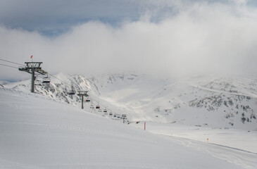 Spring alp scenery from Molltal glacier. Ski slope and chair lift in foggy april day.