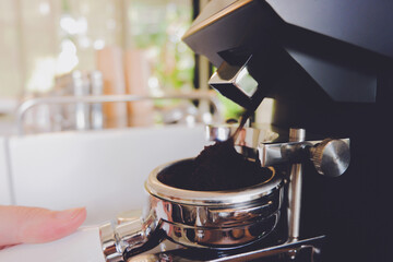 Coffee ground pouring into a portafilter from a grinder.