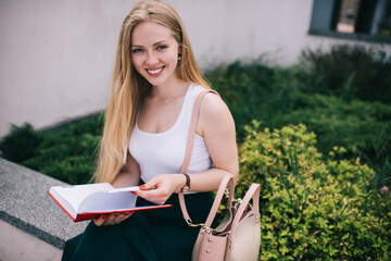 Laughing young female reading book in street