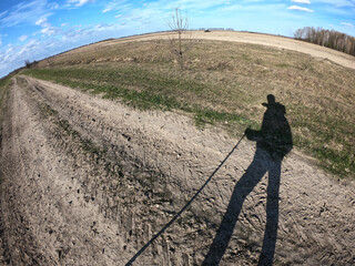 Shadow of a traveler with a cane in his hand. Landscape shot on fisheye lens.