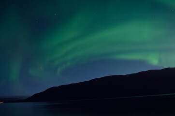 majestic aurora borealis dancing over mountain island and fjord in autumn night