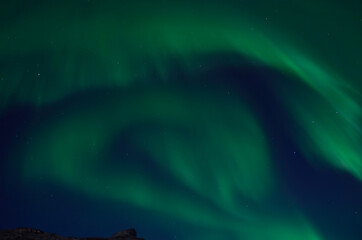 massive swirly northern light dancing over mountain top in autumn night