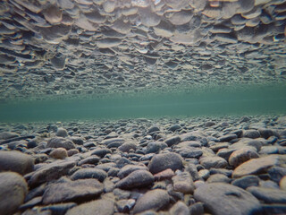cold underwater river bed with perfect reflection on surface tension