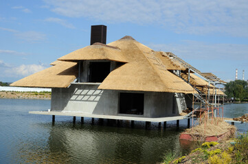 Naklejka premium stilt house by the river with the roof of their natural reeds