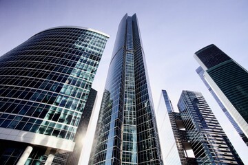 Naklejka premium Office and residential skyscrapers on bright sun and clear blue sky background. Commercial real estate. Modern business city district. Office buildings exterior. Financial city district. City downtown