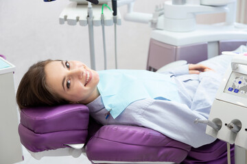 Happy smiling woman  lying on dental chair before teeth examination and treatment in dental clinic. 