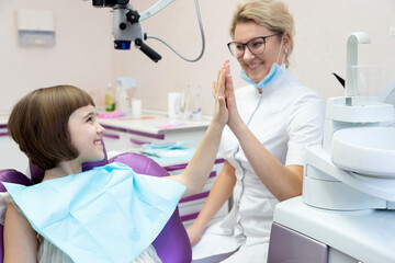 Cute smiling girl giving high five to doctor after successful treatment procedure. 