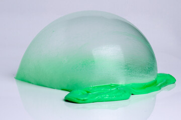 Child plays with green slime over light gray background.