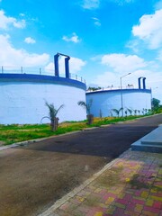 sewage water treatment plant tank or waste water recycle tank under blue sky. Road also see in the picture and palm trees are planted in road side