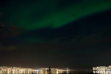 Fototapeta premium majestic aurora borealis on night sky over the city of tromsoe