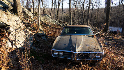 Dirty rusty black retro car abandoned on rocky hill in suburbs