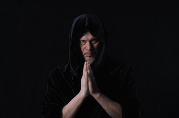 portrait of a medieval monk with a hood on a black background