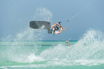 kiter does a difficult trick on a background of transparent water and blue sky