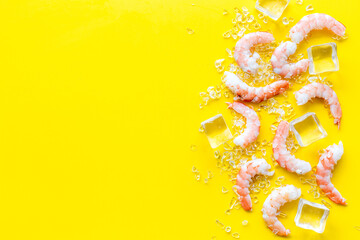 Shrimps - peeled, with ice - on yellow background frame space for text