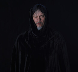portrait of a medieval monk with a hood on a black background