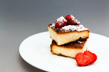 Cottage cheese casserole with strawberries on grey background, closeup view