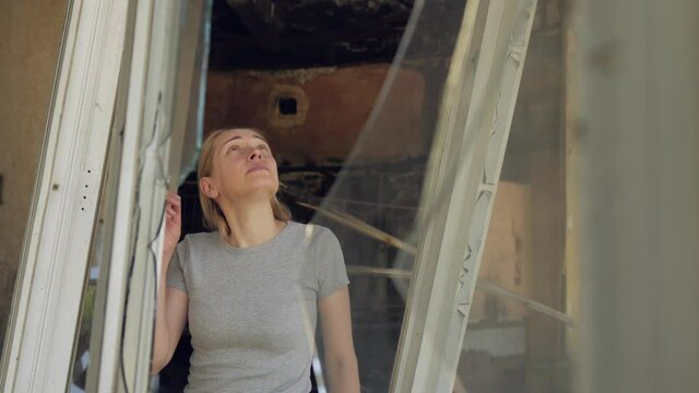 A woman inspects a house destroyed by riots