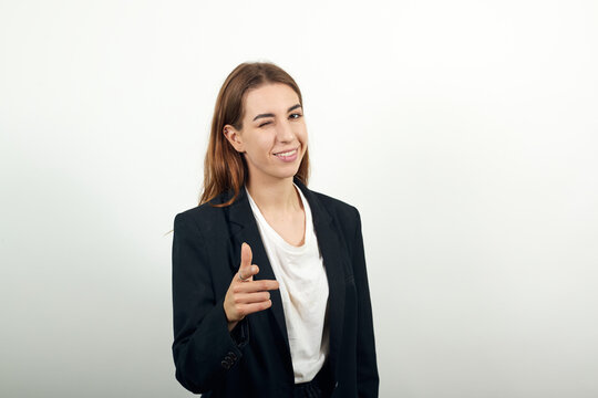 Showing thumb up, like sign positive something good has happened finger gesture for fine result well done. Winks an eye. Young attractive woman with brown hair in a light t-shirt and black jacket