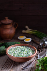 Traditional Russian cold soup okroshka with kefir in bowl on dark wooden background