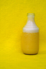 Glass bottles filled with fresh homemade yellow banana and peach smoothies