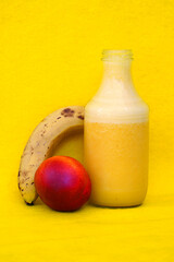 Glass bottles filled with fresh homemade yellow banana and peach smoothies