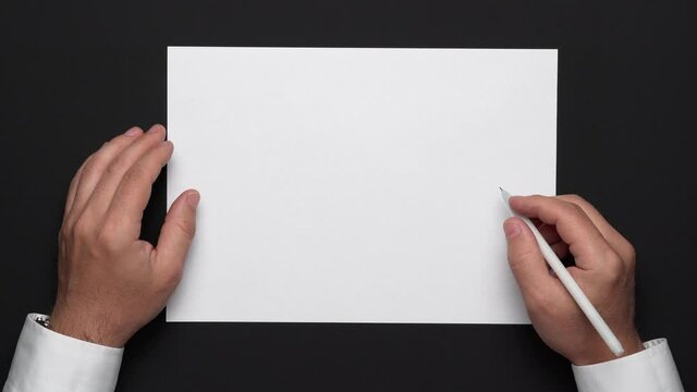 top view of a blank sheet of paper and a businessman's hands on a black table, white shirt and wrist watch