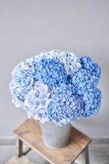 Beautiful blue hydrangea flowers in a vase on a table . Bouquet of light pink flower. Decoration of home. Wallpaper and background. © malkovkosta