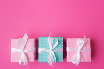 Blue and pink gift boxes with white bows on rose background with copy space