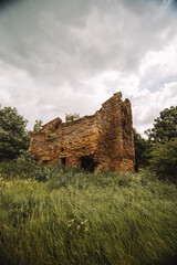 Abandoned building with moody rainy skies and grass blowing in the wind 