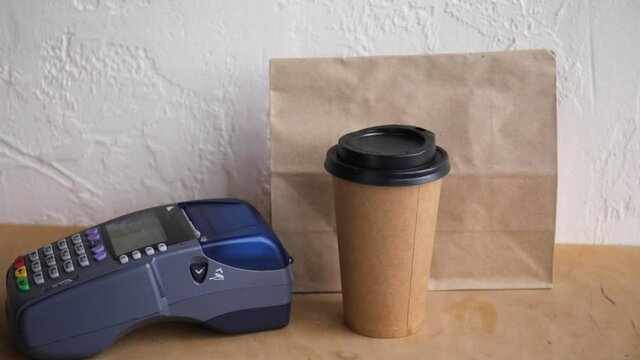 cropped view of man using credit card and payment terminal near paper bag 
