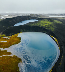 Epic landscape in Iceland. Blue crater lake on a background of black volcanic desert. Top view by drone. Vertical photo.