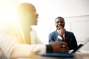 Two black african american businessman in suits talking and holding a conference in the office in the early morning
